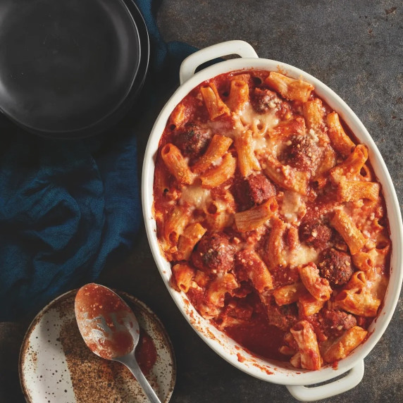 Baked pasta al forno with rigatoni, meatballs, and melted cheese in a white casserole dish.