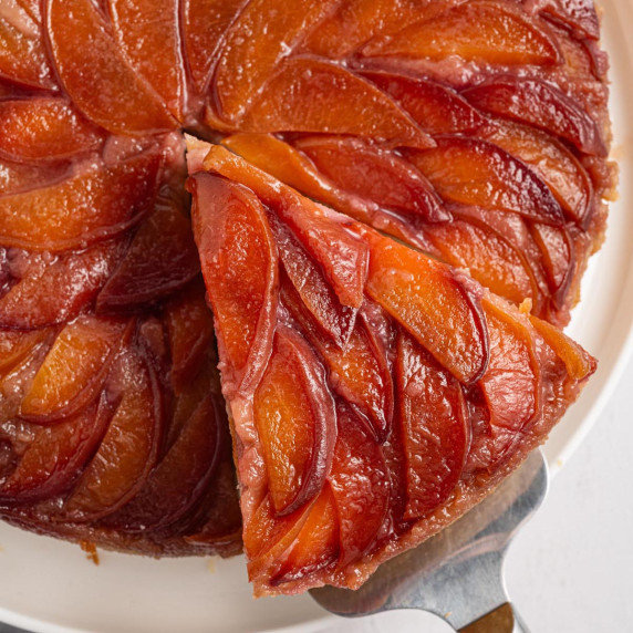 Close-up of a peach upside down cake with a slice lifted from the pan