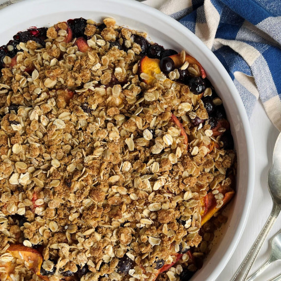 Peach and blueberry crisp in a white baking dish.