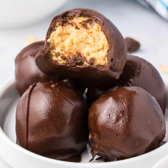 Stack of peanut butter rice krispie balls coated in chocolate with the top chocolate missing a bite 