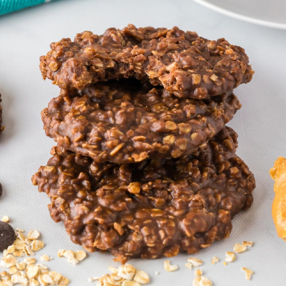 Stack of three chocolate peanut butter oatmeal cookies, with a bite taken out of the top cookie.