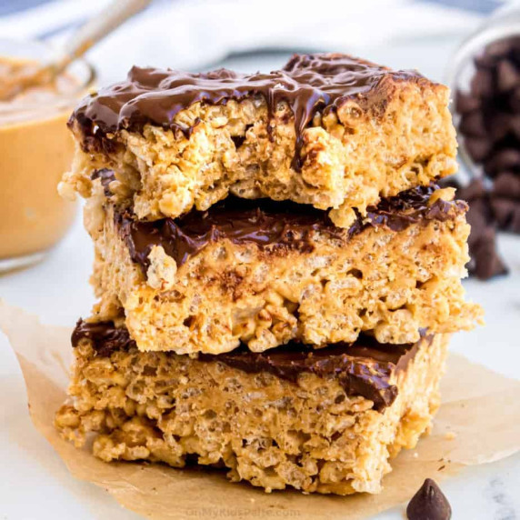 Stacked Rice Krispie treats covered in chocolate with peanut butter.