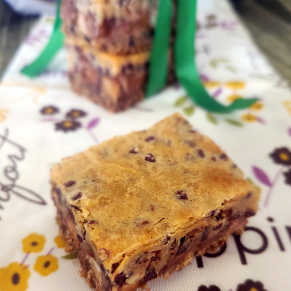 Peanut Butter Caramel Candy Bar Square on a table runner and more tied with a green ribbon