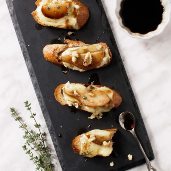 Crostini topped with brie and pear slices and drizzled with balsamic glaze.