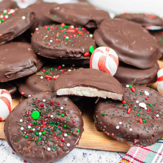 Close up of a stack of peppermint patties stacked on a cutting board with one with a bite.
