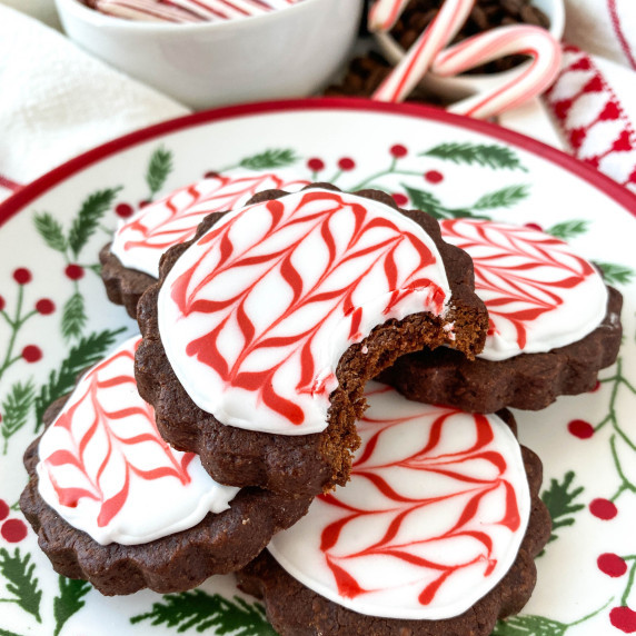 stack of peppermint mocha cookies with red and white royal icing on a christmas plate