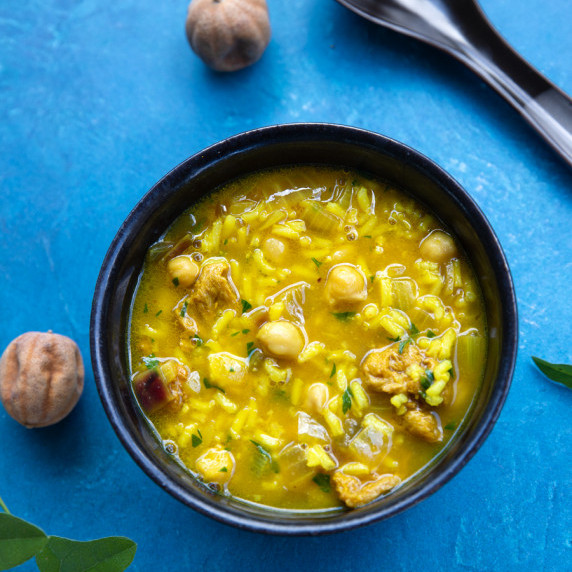 A bowl of soup surrounded by dry limes.