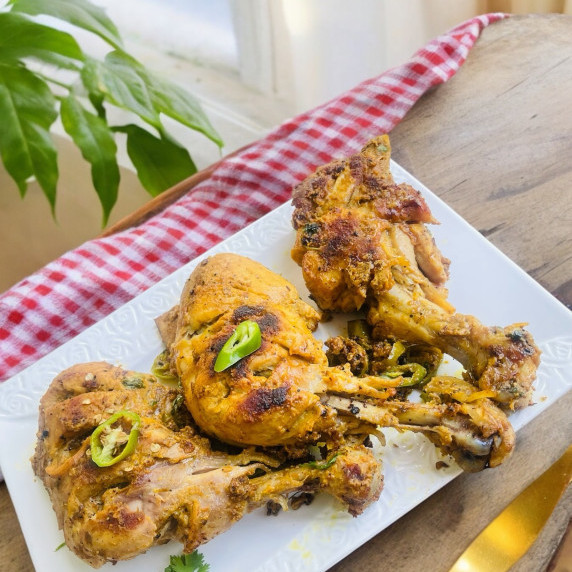 Tawa chicken arranged on white dish placed on wooden table