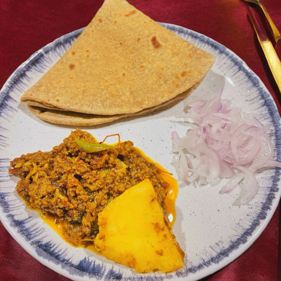 Aloo keema arranged in plate placed on dark linen