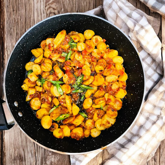 Taro root curry arranged in pan placed on wooden table