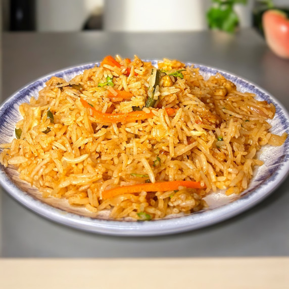 Spicy chicken fried rice arranged in plate placed on grey countertop 