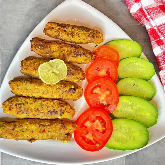 Chicken seekh kabab arranged in white dish placed on grey countertop