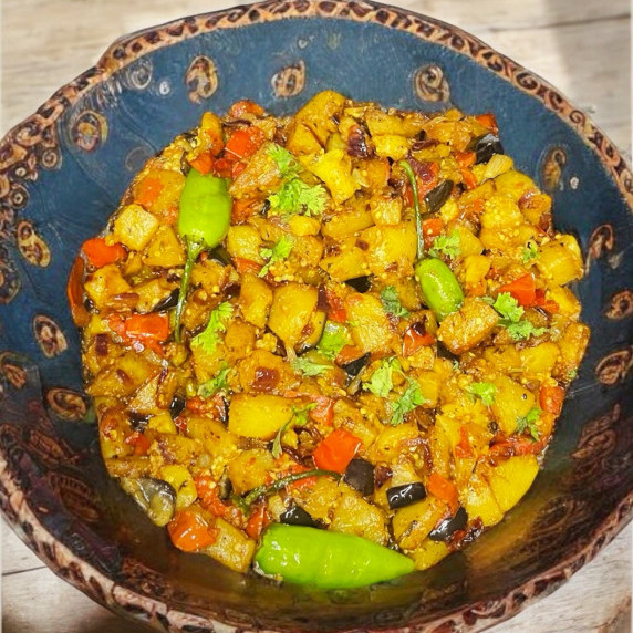 Aloo baingan arranged in blue bowl places on neutral countertop 