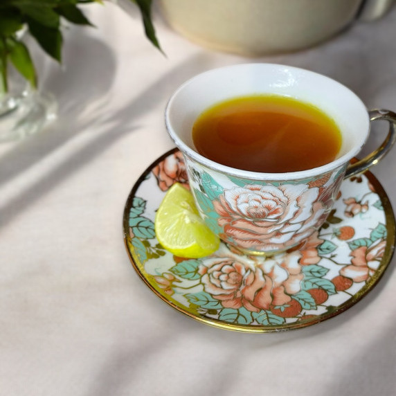 Lemon ginger turmeric tea in a floral cup placed on neutral linen