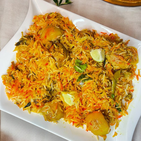 Pakistani chicken biryani arranged in white dish placed on neutral linen