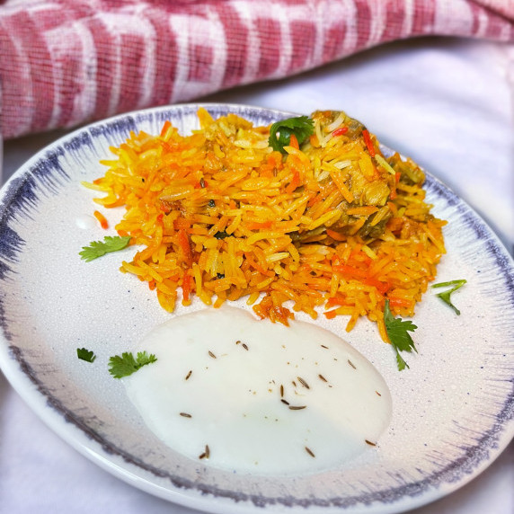 Chicken biryani placed in grey plate on white linens 