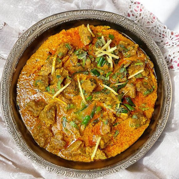 Beef tikka masala arranged in silver plate on white linen 