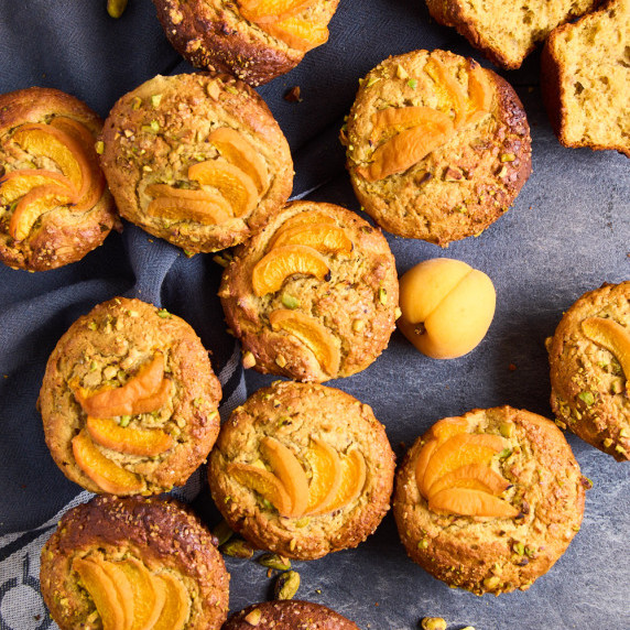 Pistachio Muffins with Apricots and Protein on a dark slate background, surrounded by fresh apricots