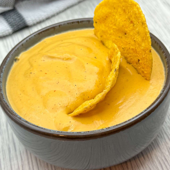 Plant-based queso-style dip made from cashews and soy milk with nutritional yeast served in a bowl w