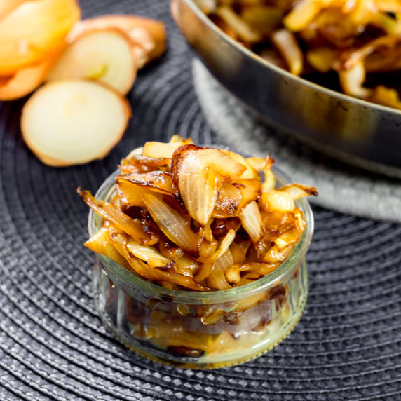 Caramelized Onions in a glass jar on a gray mat.