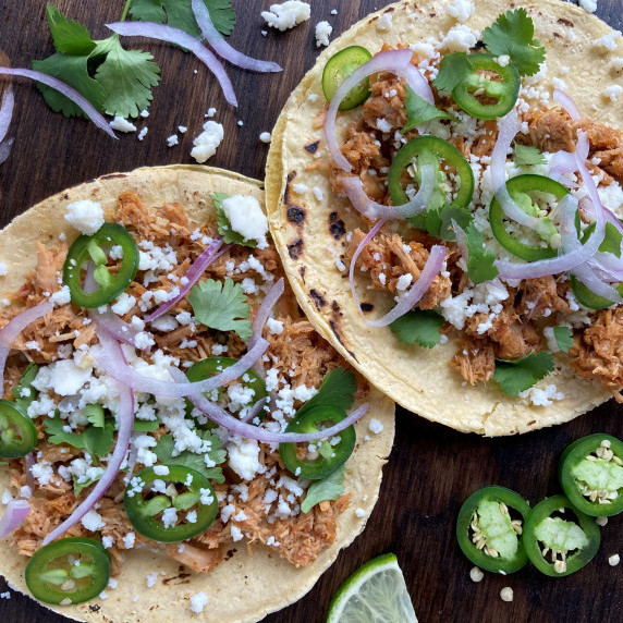 Shredded pork on corn tortillas topped with cheese, onion and jalapeño slices.