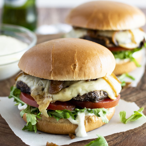 Two portobello mushroom burgers on a wooden board.