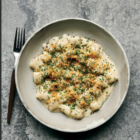 Bowl of potato gnocchi topped with Fontina cheese sauce, crispy shallots, and chives.