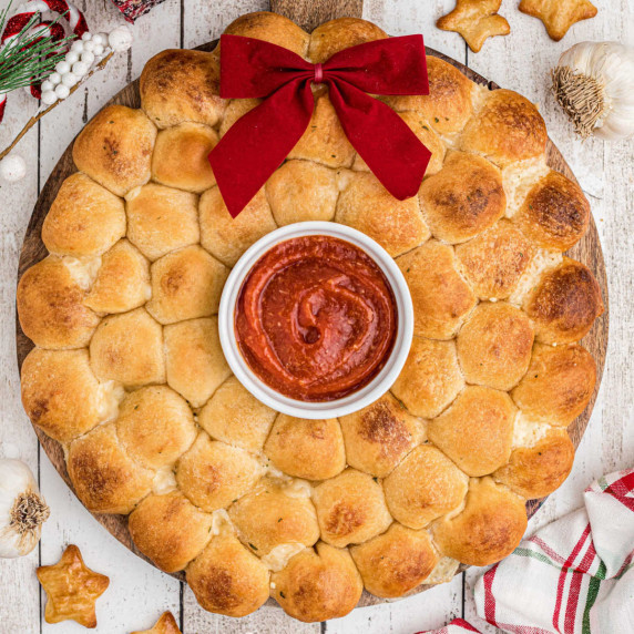 A wreath shaped pull apart bread for christmas with a dip in the center.