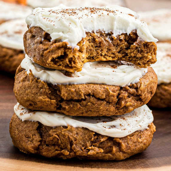 A stack of three pumpkin spice cookies with a bite taken out of one.