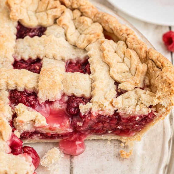 Close up of a raspberry pie with a slice missing.