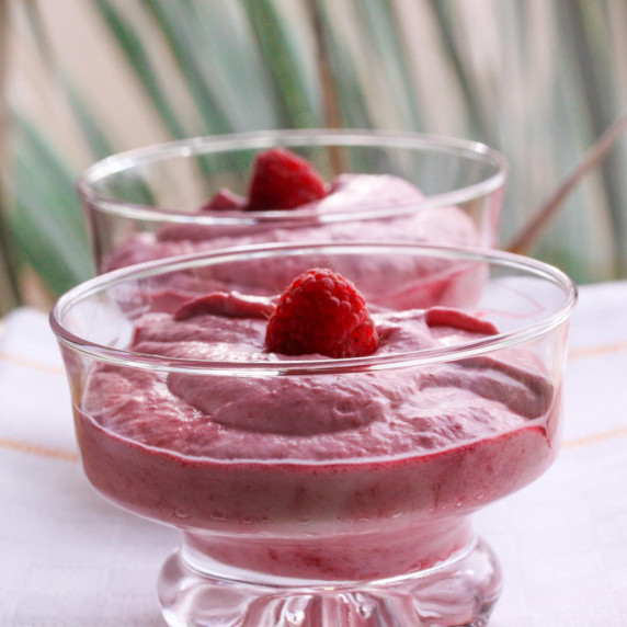 raspberry dessert displayed in 2 glass cups topped with a fresh raspberry