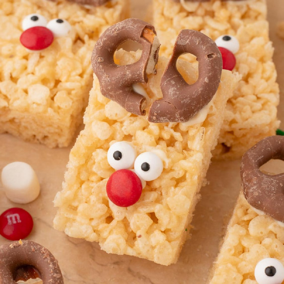 Rice Krispie treats decorated as reindeers with chocolate pretzel antlers, candy eyes, & red noses.