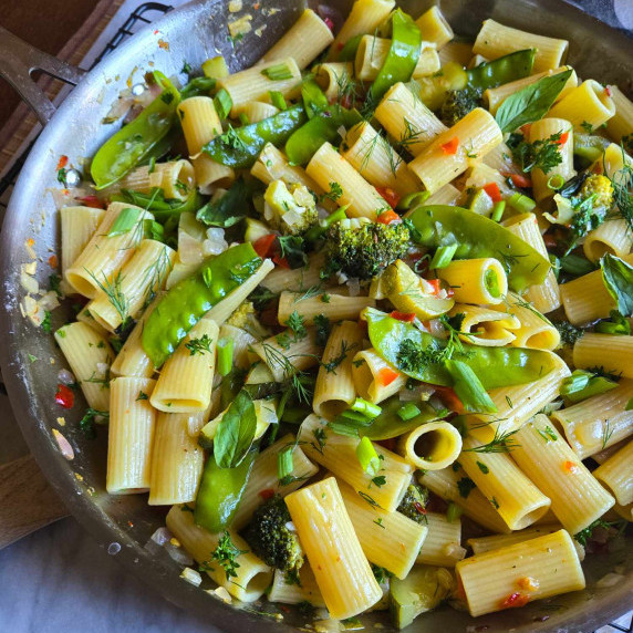 An assortment of colourful veggies and herbs along with tender rigatoni pasta