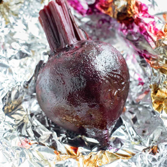 How to Roast Beets RECIPE with one roasted beet sitting on crinkled tin foil.