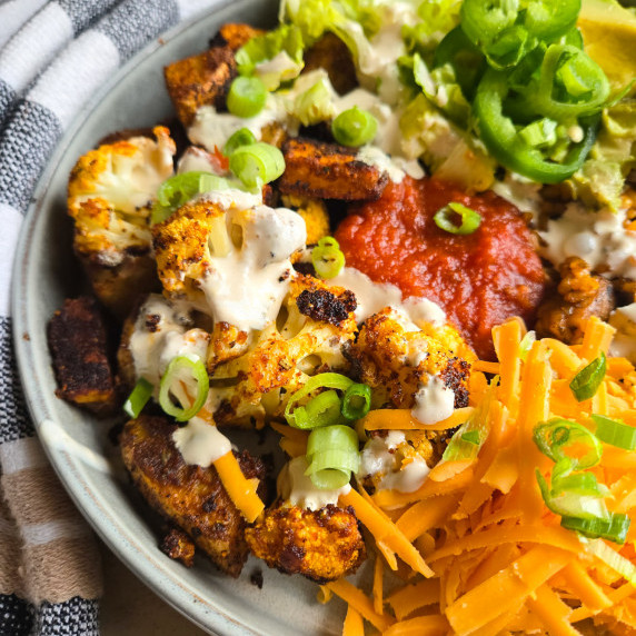 A colourful array of veggies and cheese smothered in white queso