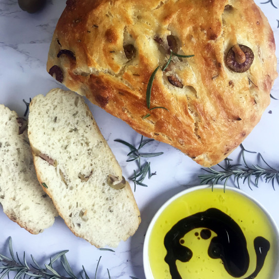 Rosemary and Olive Bread on a marble slab with rosemary, oil and vinegar.