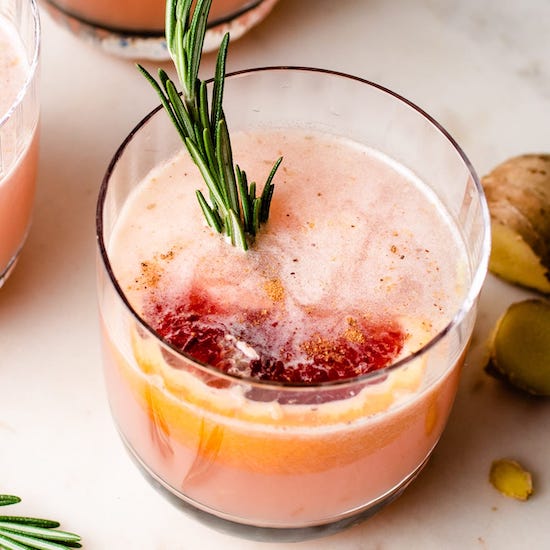 Sake grapefruit cocktail in a glass with a sprig of rosemary