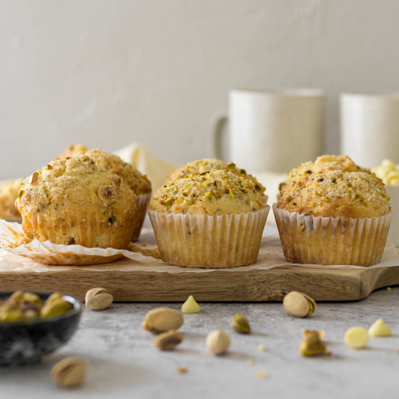 Pistachio muffins on a wooden board.