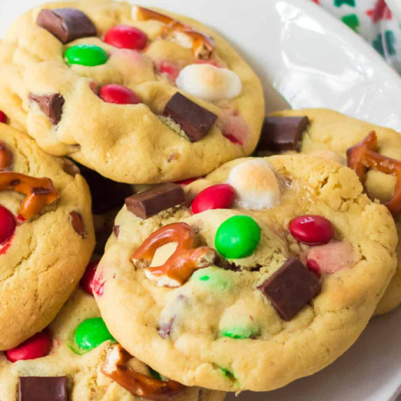 M&M chocolate chip cookies with pretzels and marshmallows up close stacked in a pile on a platter.