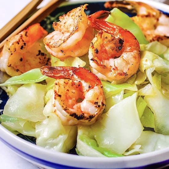 Sauteed cabbage and shrimp in a white bowl with chopsticks