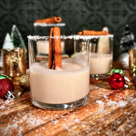 Coquito in a cocktail glass garnished with a cinnamon stick.