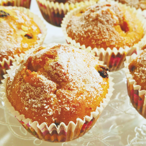 Orange-spiced muffins with pecans and cranberries, dusted with powdered sugar.