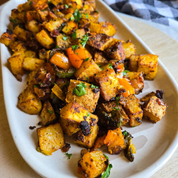 A plate of golden, oven baked potatoes with pops of green parsley.