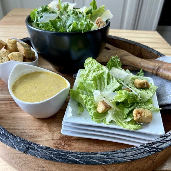 Plate of Caesar salad with a bowl of Caesar dressing on the side