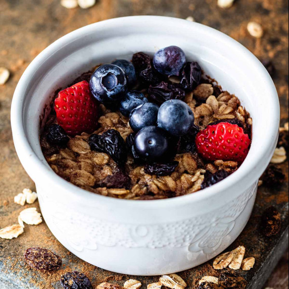 Baked oatmeal in a white ramekin topped with fresh berries.