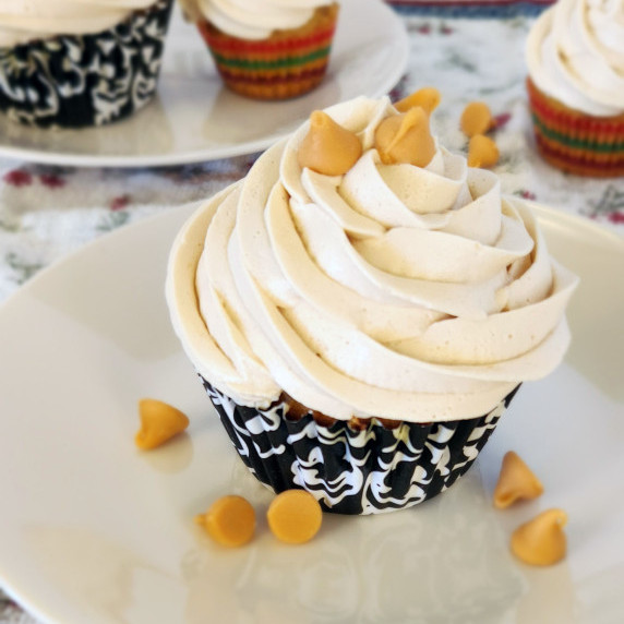 A scotchkin cupcake on a plate with butterscotch chips, more cupcakes in the background