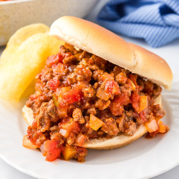 A very full sloppy joe on a plate with chips.