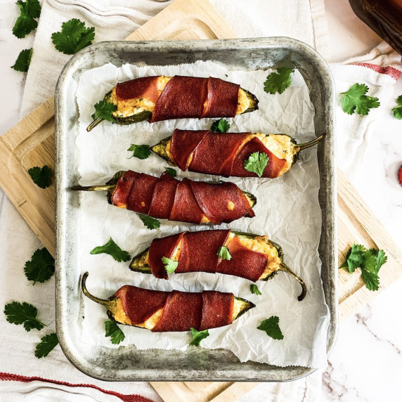 tray of smoked jalapeno poppers on a cutting board on a white counter with cilantro sprinkles