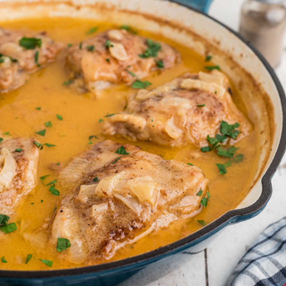 Close up of a skillet with smothered chicken.