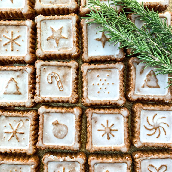 photo of glazed soft gingerbread cookies lined up taken from above with rosemary in one corner
